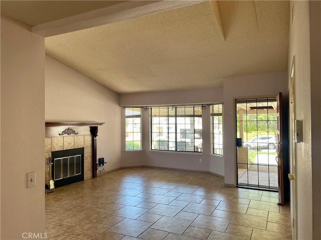 unfurnished living room with a textured ceiling, a tile fireplace, and vaulted ceiling