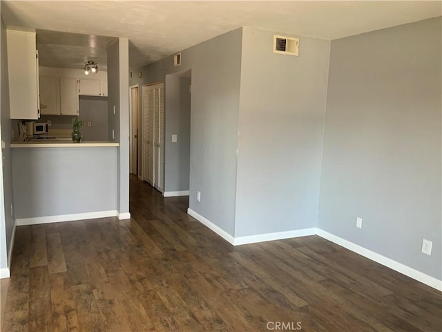 unfurnished living room with dark wood finished floors and baseboards
