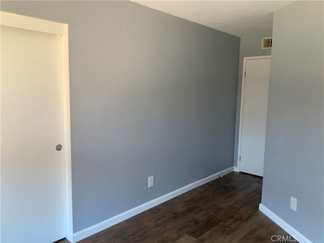 unfurnished room with dark wood-style floors and baseboards
