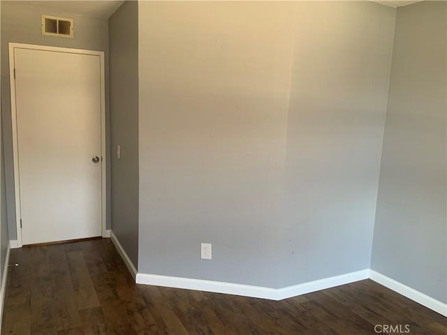empty room with baseboards and dark wood-type flooring