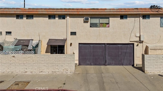 back of house featuring stucco siding, driveway, a garage, and fence