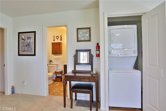washroom with stacked washing machine and dryer, light colored carpet, and baseboards