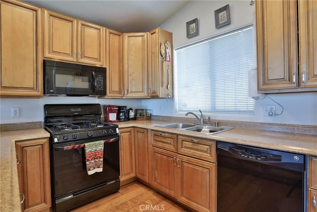 kitchen with black appliances, a sink, light countertops, and light wood-style flooring