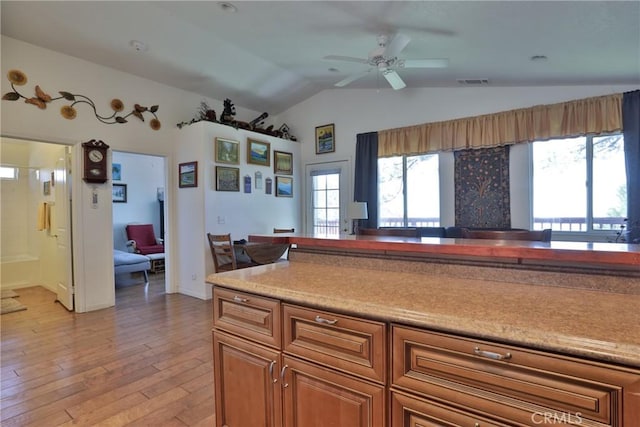 kitchen featuring vaulted ceiling, brown cabinets, ceiling fan, light wood-type flooring, and light countertops