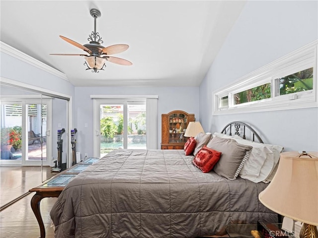 bedroom with access to exterior, lofted ceiling, multiple windows, wood finished floors, and a ceiling fan
