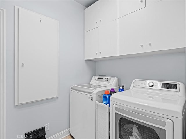 clothes washing area featuring washer and clothes dryer, cabinet space, and baseboards