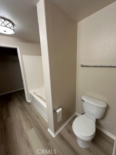 31256 Taylor Ln, Temecula, CA 92592 - bathroom with wood finished floors, toilet, baseboards, and a spacious closet