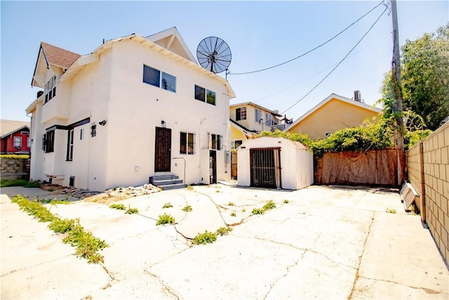 back of property featuring a shed, a fenced backyard, stucco siding, and an outdoor structure
