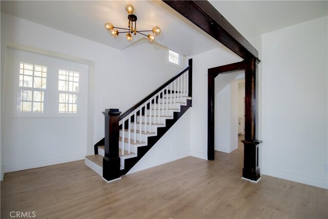 entryway with stairs, a chandelier, wood finished floors, and baseboards