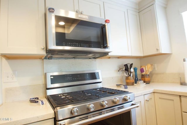 kitchen featuring stainless steel appliances, light countertops, white cabinetry, and decorative backsplash