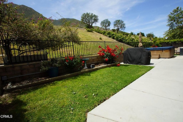 view of yard featuring a hot tub, a mountain view, and a patio