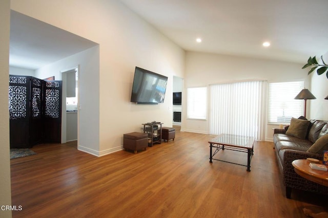 living room featuring lofted ceiling, wood finished floors, baseboards, and recessed lighting