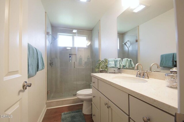 full bath with toilet, a stall shower, vanity, wood finished floors, and baseboards