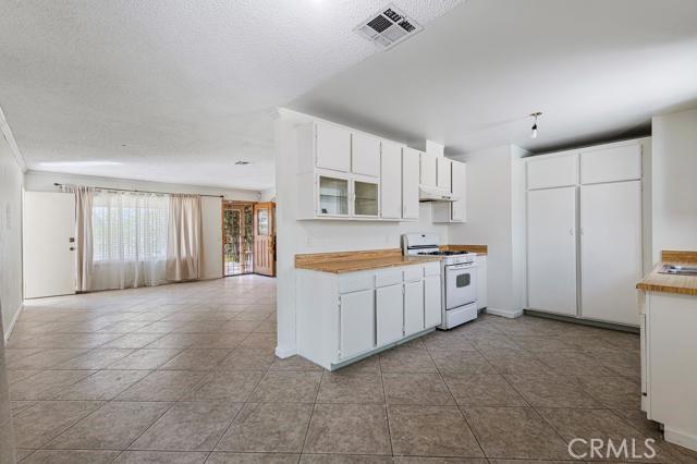 1880 Sharon Rd, Palm Springs, CA 92262 - kitchen featuring white gas stove, under cabinet range hood, white cabinets, and light tile patterned floors