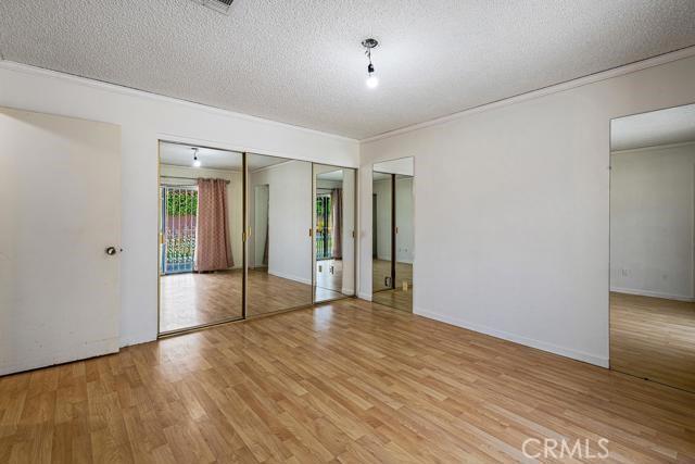 1880 Sharon Rd, Palm Springs, CA 92262 - unfurnished bedroom featuring light wood-style flooring, a textured ceiling, crown molding, and baseboards