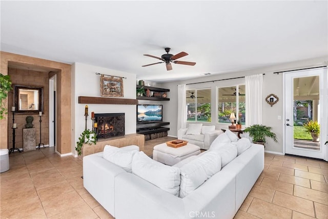 35475 Calendula Cir, Winchester, CA 92596 - living room featuring ceiling fan, a lit fireplace, light tile patterned floors, and baseboards