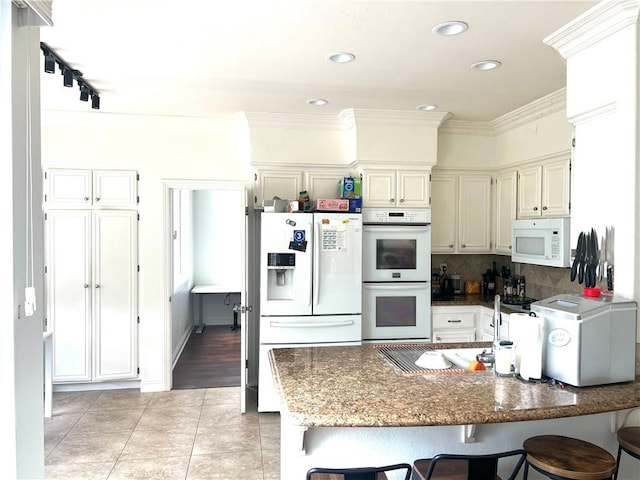 13564 Esprit Ave, San Diego, CA 92128 - kitchen with white appliances, light tile patterned flooring, a peninsula, dark stone countertops, and a breakfast bar