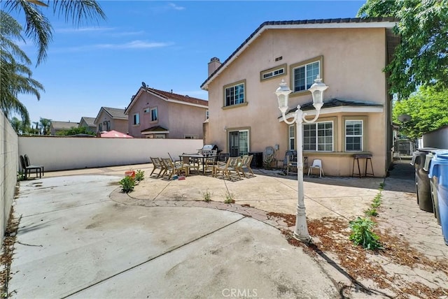 1451 W 10th St, Pomona, CA 91766 - rear view of house with stucco siding, a chimney, fence, a patio area, and outdoor dining space