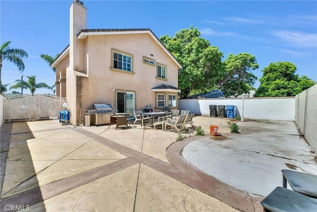 1451 W 10th St, Pomona, CA 91766 - back of house with a chimney, a patio area, a fenced backyard, stucco siding, and outdoor dining space