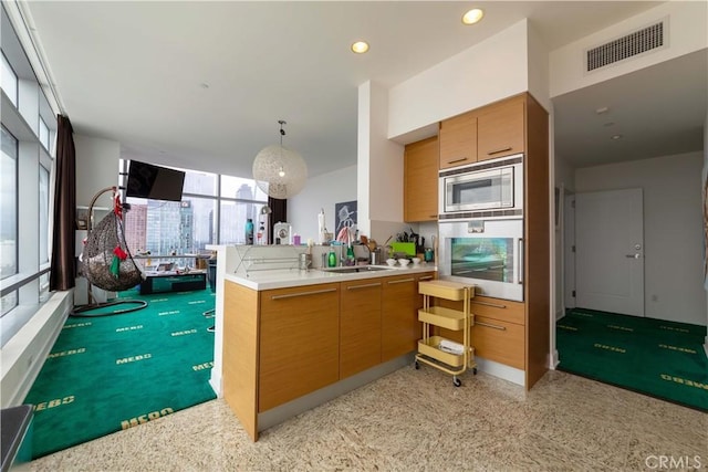 kitchen featuring appliances with stainless steel finishes, a peninsula, a sink, light countertops, and open floor plan