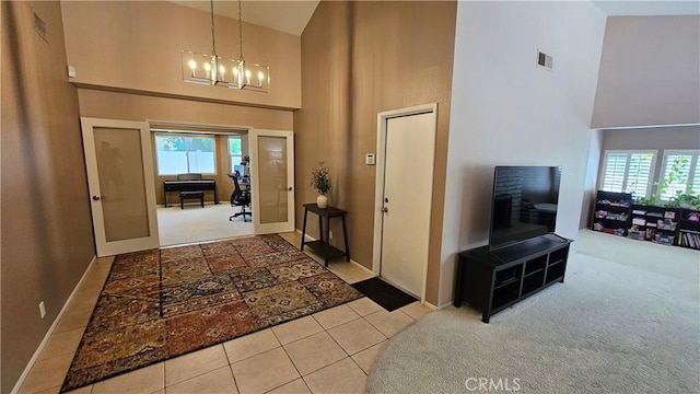 entryway with high vaulted ceiling, carpet, baseboards, a chandelier, and tile patterned flooring
