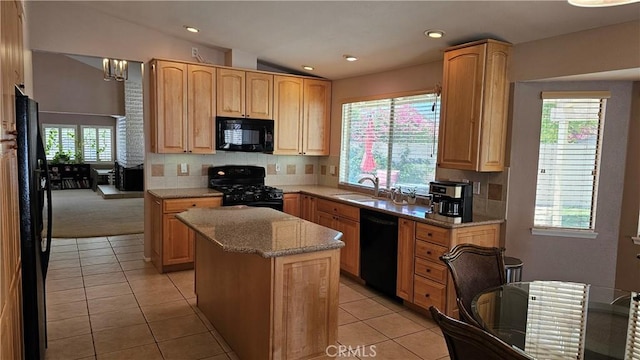 kitchen featuring black appliances, decorative backsplash, a kitchen island, light stone countertops, and vaulted ceiling