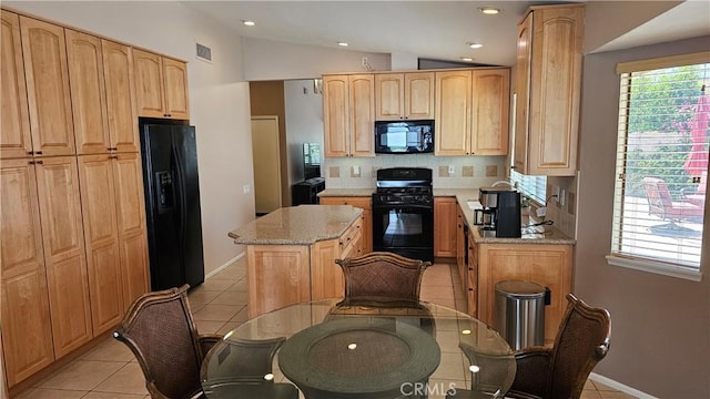 kitchen with black appliances, a center island, light tile patterned floors, decorative backsplash, and light stone counters