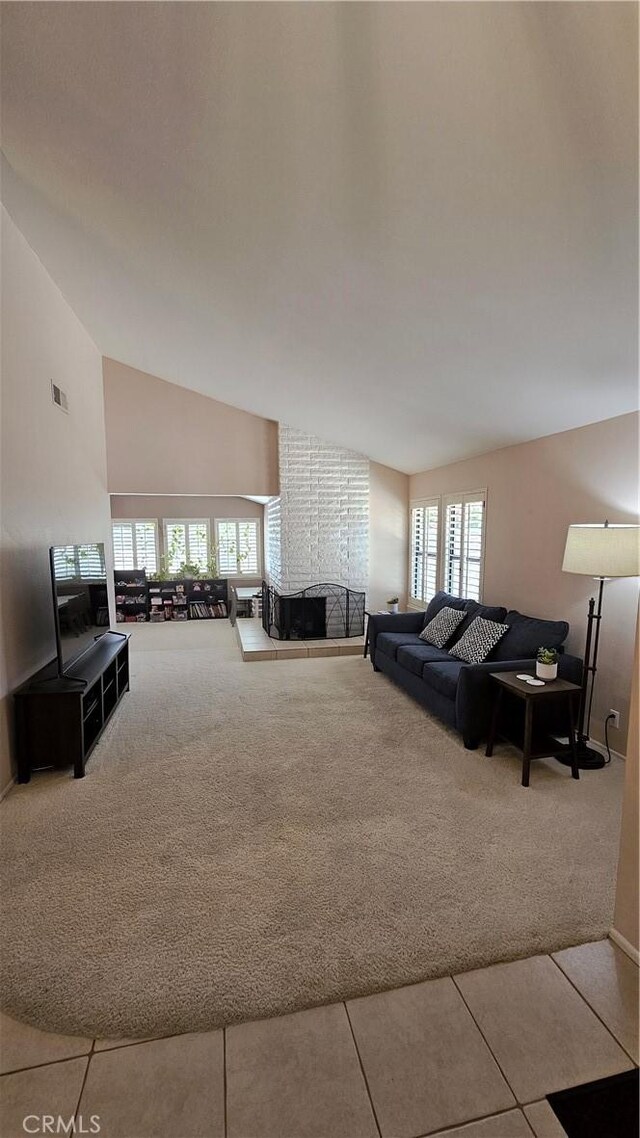 tiled living room with carpet, plenty of natural light, a brick fireplace, high vaulted ceiling, and baseboards