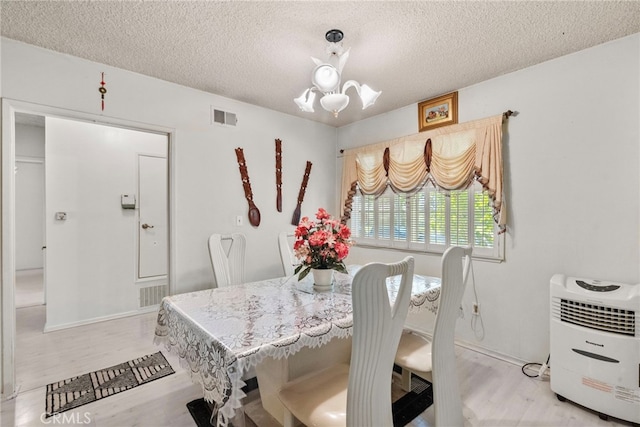 11242 Kamloops St, Sylmar, CA 91342 - dining room featuring light wood-style floors, a chandelier, and a textured ceiling