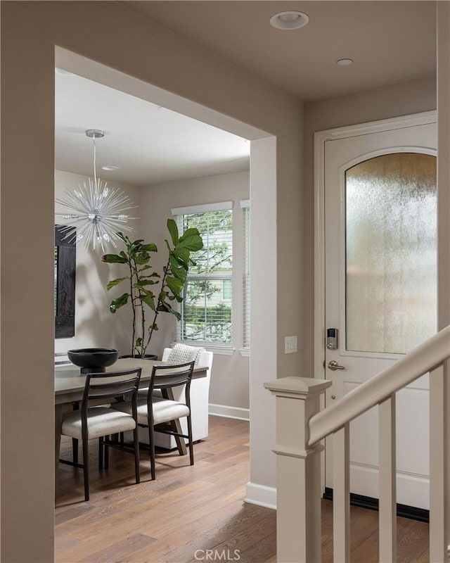 foyer entrance featuring baseboards, wood finished floors, recessed lighting, and a chandelier