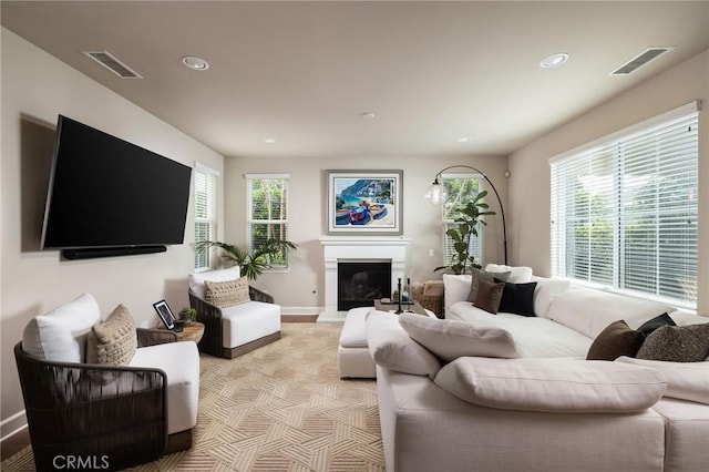 living area with healthy amount of natural light, baseboards, recessed lighting, and a glass covered fireplace