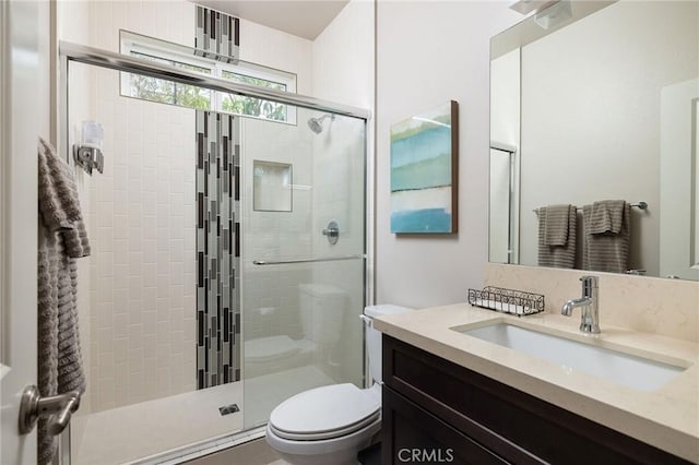 full bathroom featuring a stall shower, toilet, and vanity