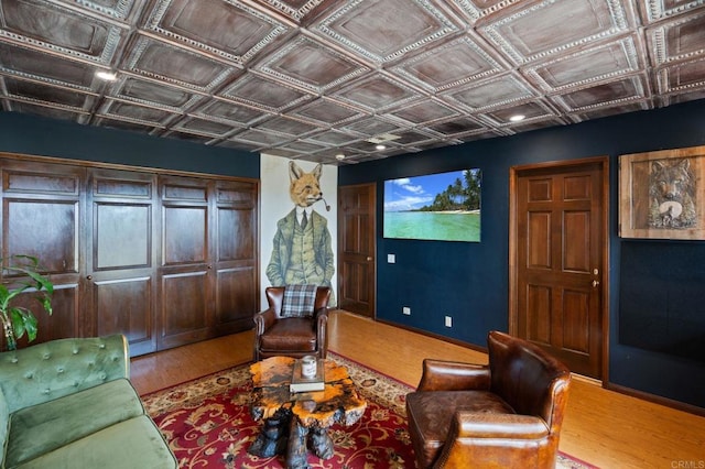 home theater with wood finished floors, an ornate ceiling, and baseboards