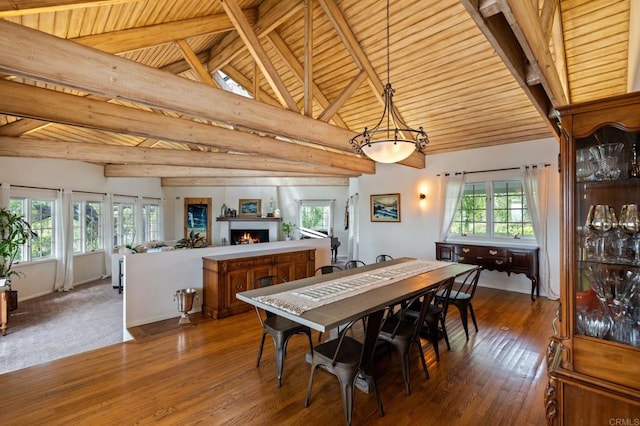 dining space featuring a warm lit fireplace, hardwood / wood-style floors, and wooden ceiling