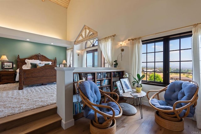 bedroom featuring wood finished floors, high vaulted ceiling, and baseboards