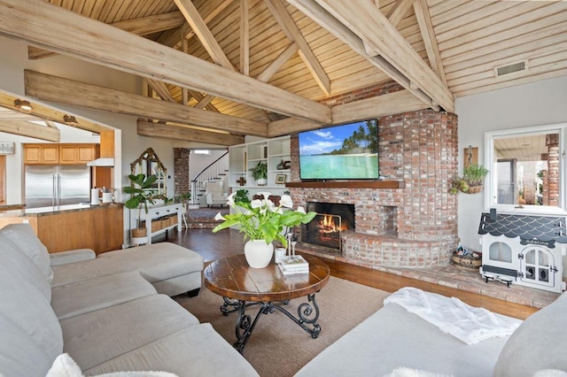 living area with stairway, wood finished floors, wooden ceiling, and an outdoor brick fireplace
