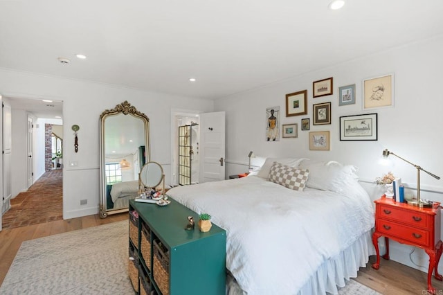bedroom with wood finished floors, ornamental molding, and recessed lighting
