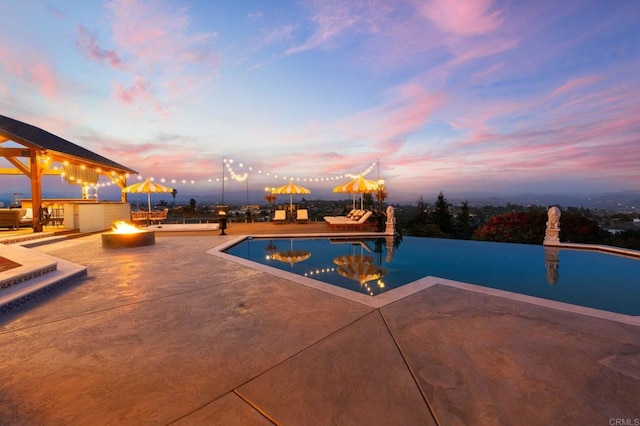 outdoor pool with a fire pit and a patio area