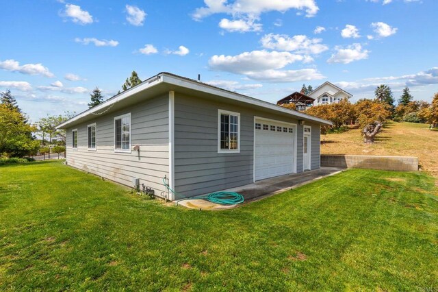 view of property exterior with a detached garage and a lawn