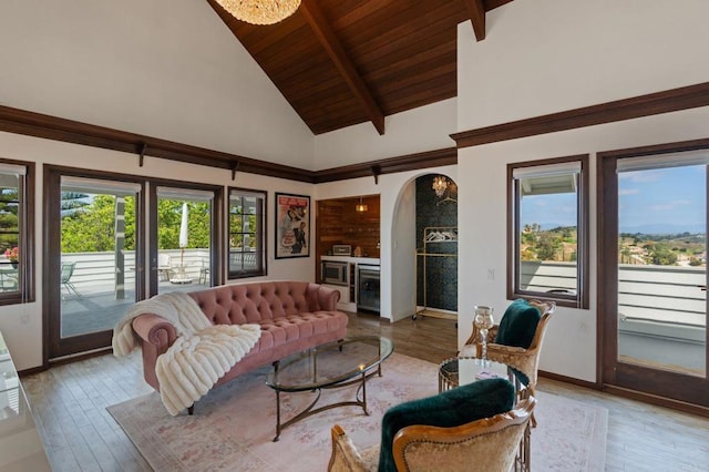 living room with arched walkways, healthy amount of natural light, light wood-type flooring, high vaulted ceiling, and wood ceiling