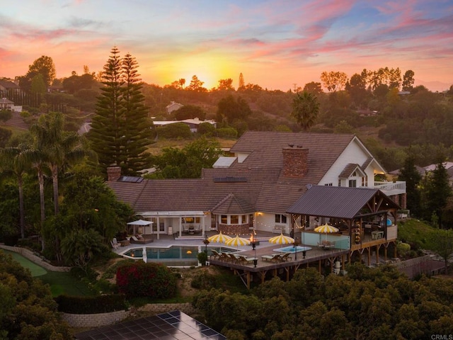 back of house with an outdoor pool, a chimney, and a patio