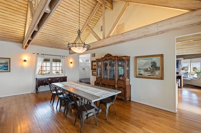 dining space featuring wood finished floors, beamed ceiling, baseboards, and high vaulted ceiling