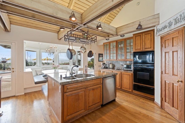 kitchen with black appliances, a sink, wooden ceiling, brown cabinets, and a center island with sink