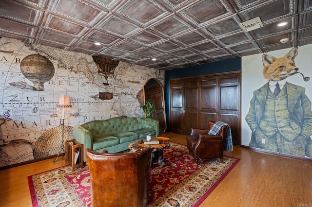 living area featuring arched walkways, an ornate ceiling, and wood finished floors