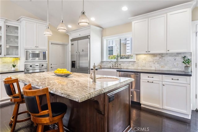2808 Oak Ave, Manhattan Beach, CA 90266 - kitchen with built in appliances, white cabinets, a kitchen island with sink, decorative backsplash, and dark stone counters