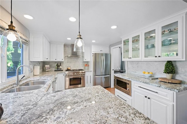 kitchen featuring stainless steel appliances, wall chimney range hood, a sink, decorative backsplash, and recessed lighting
