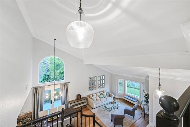 living area with vaulted ceiling, wood finished floors, and crown molding