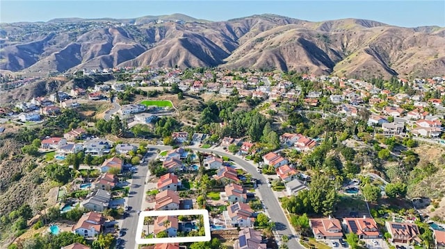 aerial view of property and surrounding area with a mountainous background and nearby suburban area