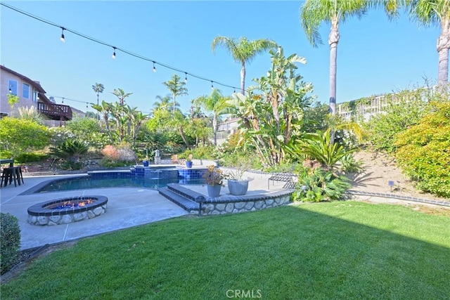 view of grassy yard featuring a patio and a fire pit