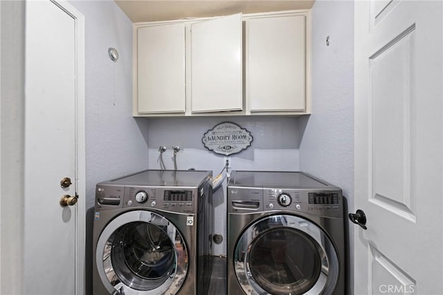 clothes washing area featuring cabinet space, separate washer and dryer, and a textured wall